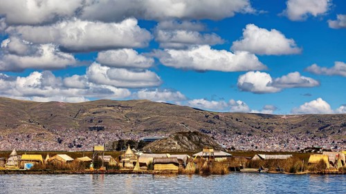 Village with traditional lakeside buildings surrounded by hills and clouds, The floating reed