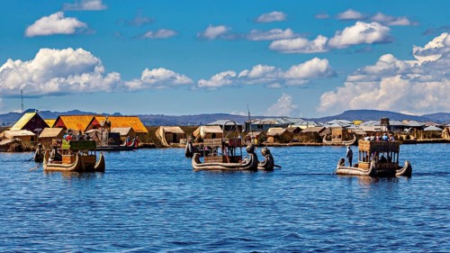Several boats near a collection of reed huts on the lake, The floating reed islands of the Uros in