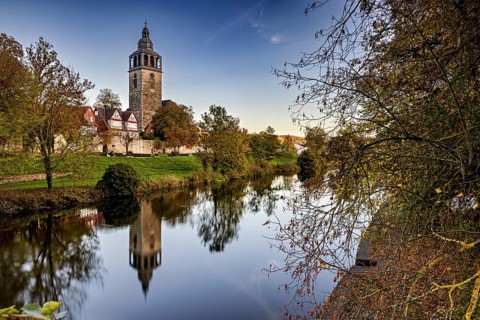 Church on the river, surrounded by autumnal trees with beautiful reflections in calm water, The