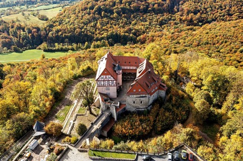 Historic castle surrounded by autumnal forest in a beautiful landscape taken from the air,