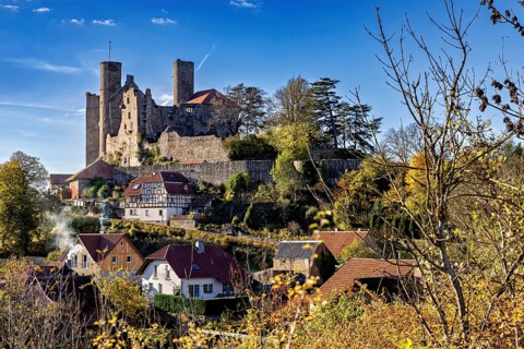 Medieval castle above a village with autumn trees under a blue sky, Hanstein Castle near Bornhagen