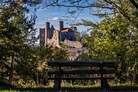 Bench in the foreground, medieval castle surrounded by trees, autumnal atmosphere, Hanstein Castle