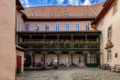 A quiet courtyard with historic half-timbered elements, balconies and decorative flowers under a