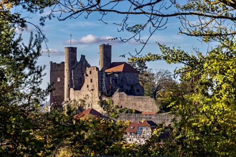 Medieval castle with stone towers, surrounded by trees under a blue sky, Hanstein Castle near