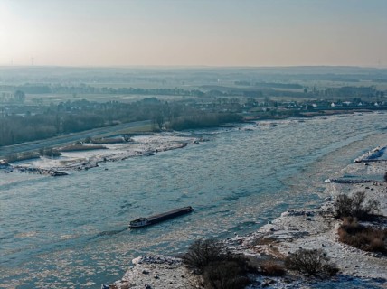 On a cold winter day, a barge sails downstream on the Elbe near Hamburg when there is slight ice.
