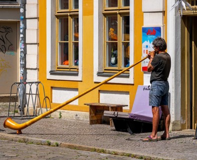 Man with an alphorn in front of the music store in Gutenbergstraße, Potsdam, Brandenburg, Germany