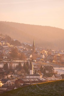 Snowy village with church and houses in a hilly area, Black Forest, Germany