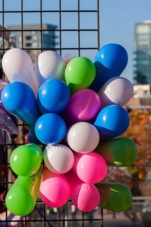 Close-up of colourful balloons inflated with helium gas and attached to black metal lattice support