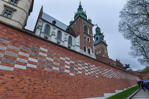 North façade of the cathedral on Wavelhügel, tourist group in the rain, Krakow, Poland