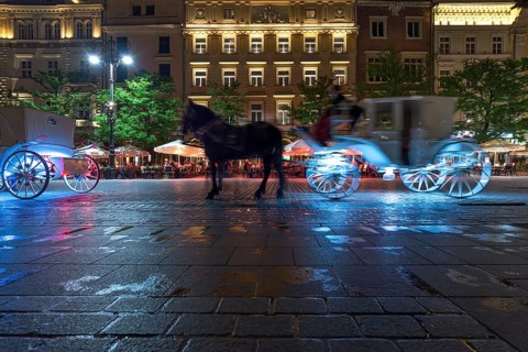 Waiting horse-drawn carriages at the market square at night, Krakow, Poland
