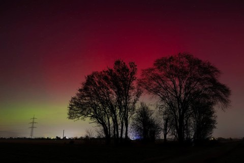 Northern lights (aurora borealis) glow red and green in the evening sky over Germany, Frankfurt am