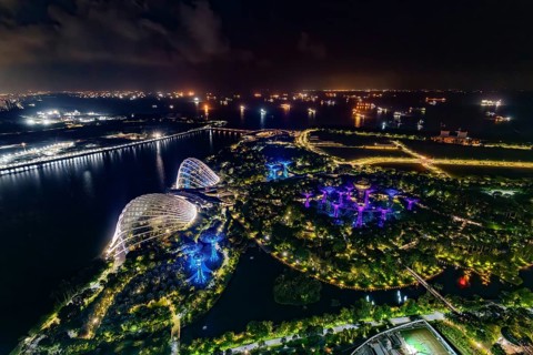 Aerial view over the illuminated Gardens by the Bay, GBTB and Supertree Grove, urban park and