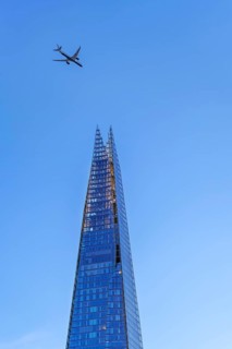 Airplane of British Airways flying over The Shard, skyscraper and tallest building in the United