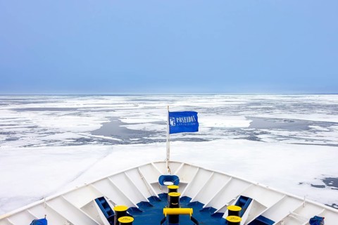 Drift ice, brash ice consists of ice floes and bow of Poseidon Expeditions cruise ship during