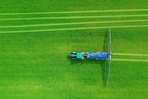 Aerial view over tractor towed liquid manure spreader, slurry spreader enabling the fertilization