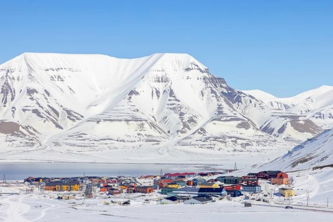 View over the town Longyearbyen on the shore of Adventfjorden and snow covered mountains in winter