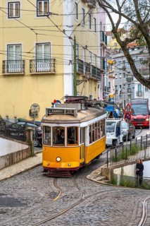 Traditional vintage yellow tram on tram line 28 climbing steep cobbled street in the capital city