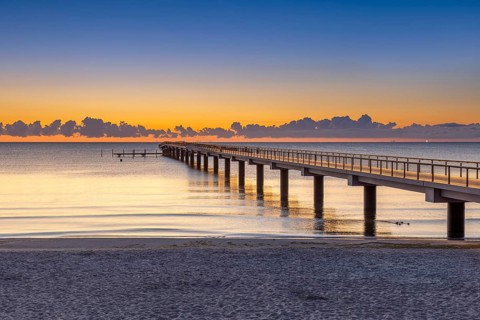 Seebrücke / pier and sandy beach at seaside resort Scharbeutz along the Baltic Sea at sunrise,