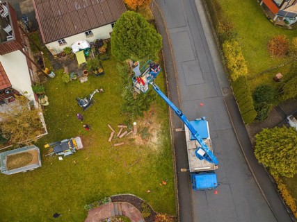 Work scene viewed from above with lift and vehicle on a green area in the suburbs, tree work,