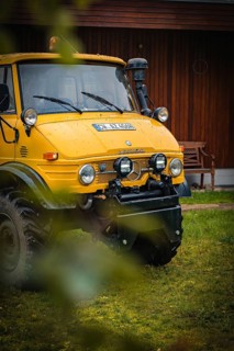 Yellow Unimog in the rain next to a wooden building in a meadow, tree work, Gechingen, Calw