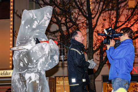 Ice carving artist in front of his ice sculpture interviewed by a GEA reporter during ice carving