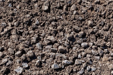 Close-up of sand mixed with grey crushed stone aggregate used to form a bed for constructing roads