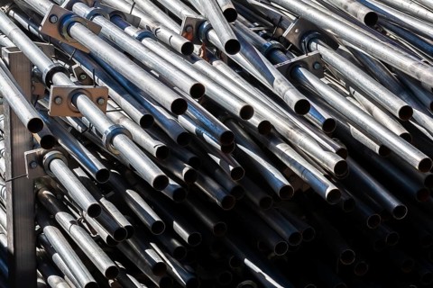 Close-up of stacked heavy duty galvanized steel poles in outdoor storage yard in early autumn,