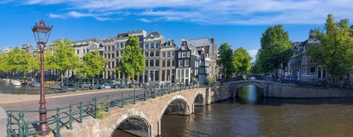 Holland, Amsterdam canals with boats, scenic bridges and historic city center, UNESCO World