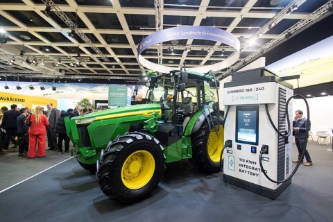 The prototype of an electric John Deere E-Power tractor is standing next to a charging station