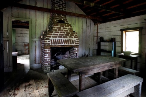 Rustic interior decor of a slave shelter with fireplace and table, Charleston, South Carolina, USA