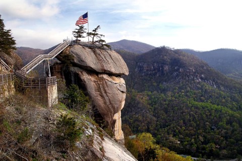 Chimney Rock with American flag and panoramic views of the forested mountains, zero