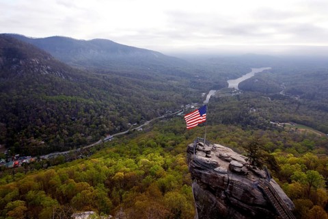 Majestic view of Chimney Rock with US flag and vast forests, zero