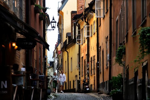 A lively old town alleyway in Stockholm, surrounded by colorful buildings and historic charm,