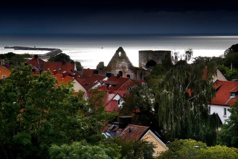 View of Visby's old town with red roofs and church ruins, surrounded by lush greenery and sea