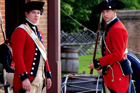 Two soldiers in red historic uniforms stand in front of a building and look alert, Williamsburg,