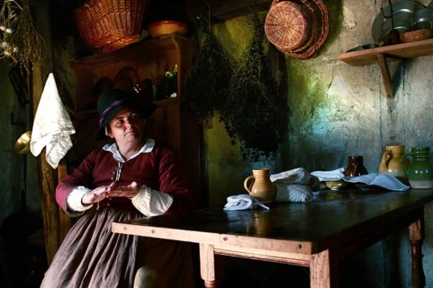 Woman wearing historical costume in a rustic house at Plimoth Plantation, Plymouth, Massachusetts,