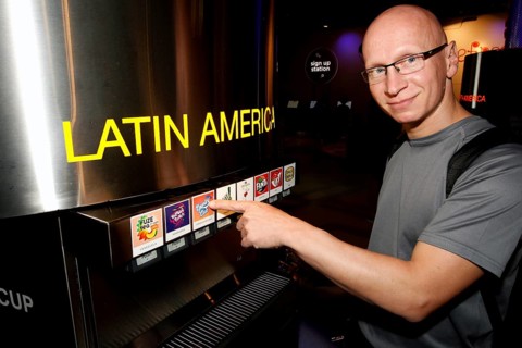 A man in the tasting room of the Coca-Cola Museum in Atlanta enthusiastically points to drinks from