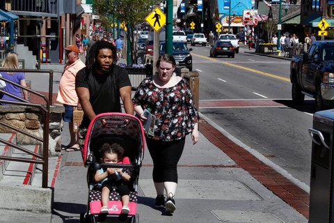 Family with stroller walking down the sunny main street of Gatlinburg, Gatlinburg, Tennessee, USA