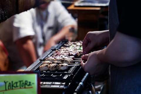Grilling yakitori skewers in a busy bar setting, Shinjuku, Tokyo, Japan