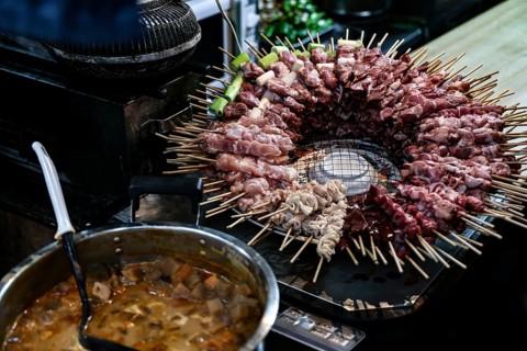 Yakitori skewers over an open grill in a bar in Shinjuku, Shinjuku, Tokyo, Japan