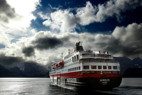 Hurtigruten ship sails through Øksfjord under cloudy sky, Øksfjord, Norway