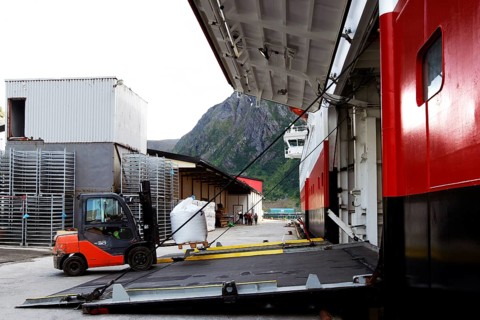 Hurtigruten ship in harbor with open cargo hatch with view of nearby mountainside, Øksfjord,