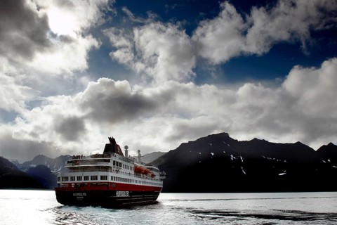Hurtigruten ship leaves Øksfjord under atmospheric sky, Øksfjord, Norway