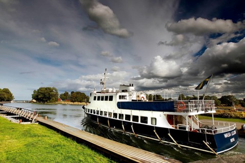 Passenger ship in the Göta Canal at a dock under a cloudy sky, mountain, Sweden