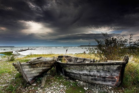 Dilapidated fishing boats on the stormy coast of Gotland under dramatic skies, Gotland, Sweden