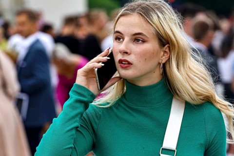 Young woman talking on the phone during a high school graduation ceremony on Cathedral Square,