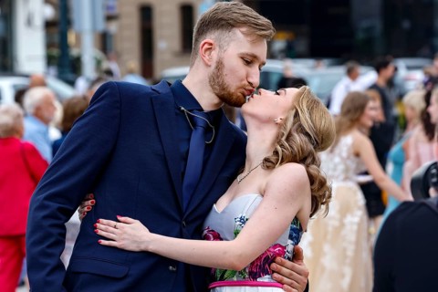 A young couple kisses during a high school graduation ceremony in a busy square, Vilnius, Vilnius