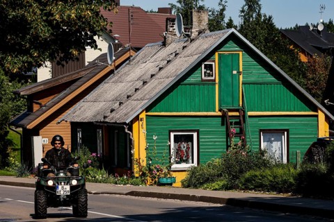 Green wooden house in Trakai with a passing ATV on the road in front of it, Trakai, Lithuania