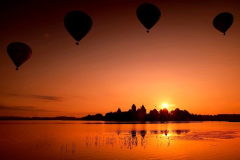 Balloons float in the morning sky over Trakai Castle at sunrise, Trakai, Lithuania