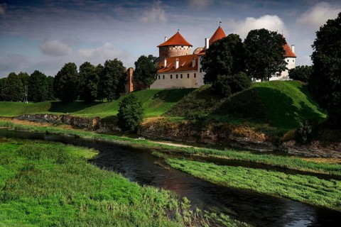 Crusader castle on Musa surrounded by green landscape and clouds in the sky, Bauska, Latvia